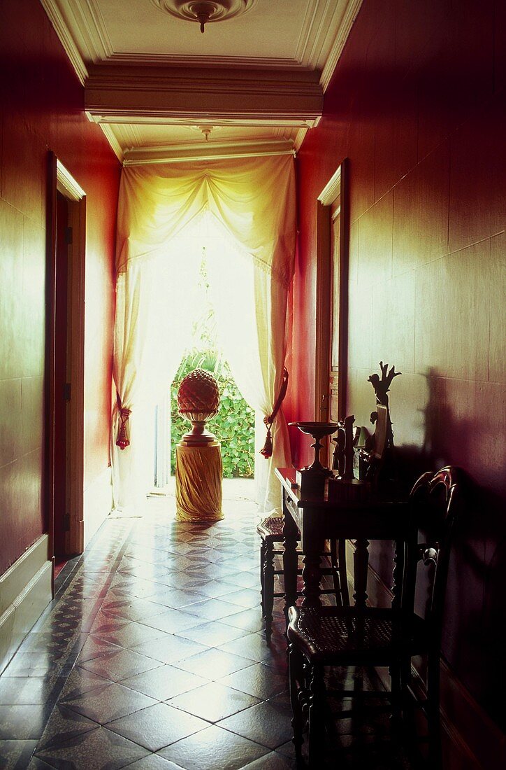 Elegant hallway with red walls, floor to ceiling window with the curtains drawn back