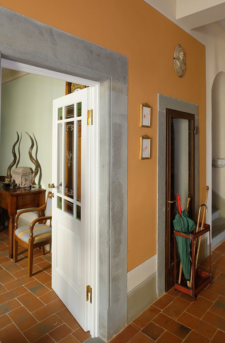 Hallway with orange walls and doorway framed with stone, open door with a view into a living room