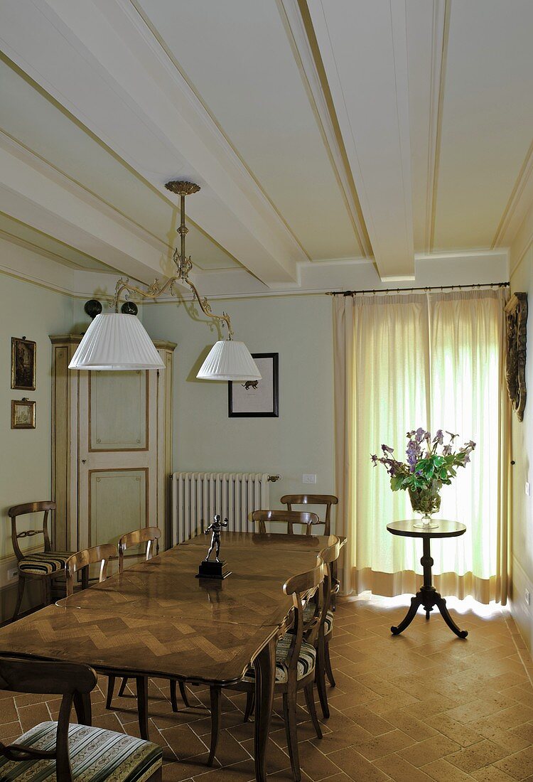 Dining room in a country home with a long table and side table in front of closed curtains