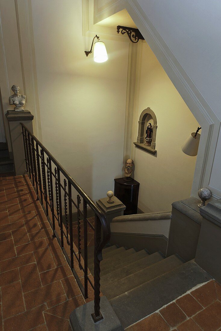 Blick auf Treppenabgang mit Wandbeleuchtung und Terrakottaboden im eleganten Landhaus