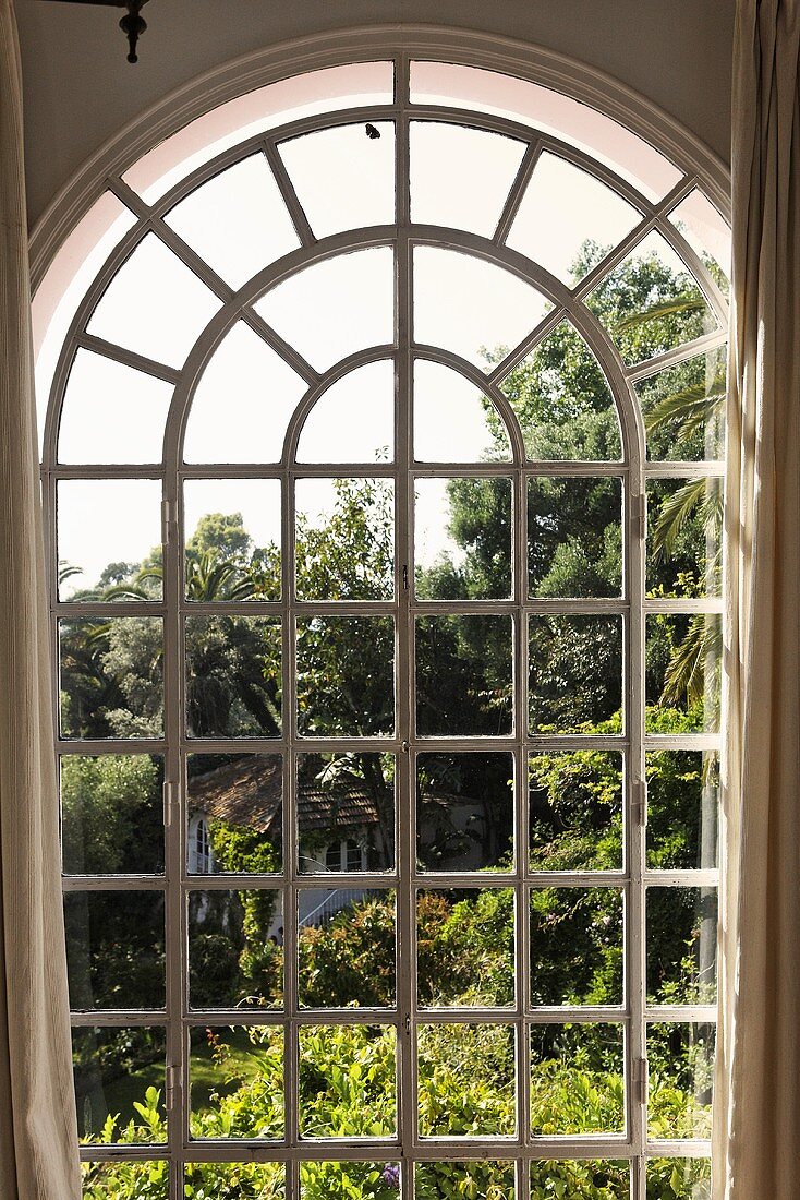 Blick durch Rundbogenfenster auf Garten
