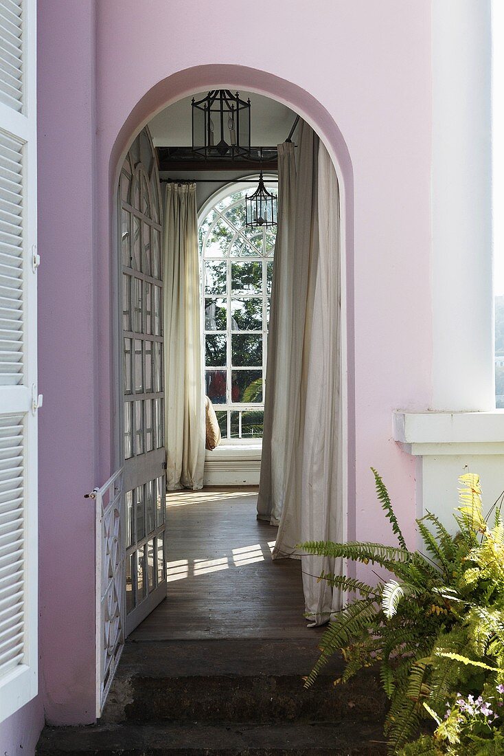 Villa with a pink facade and a view through an archway of a floor to ceiling window