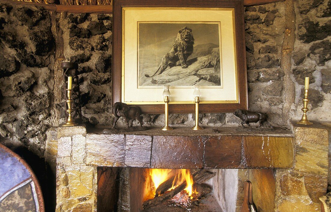 Natural stone wall with a fireplace and crackling fire with animal figurines on the mantelpiece