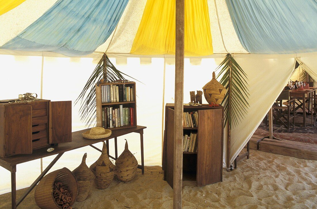 Zelt mit Kleinmöbeln und einer Holzbank im Sand