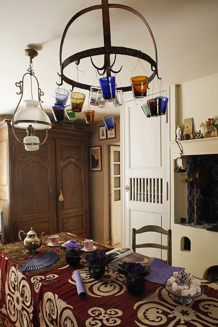 Dining table with a patterned tablecloth in oriental style and colorful tea lights hanging from a metal frame from the ceiling