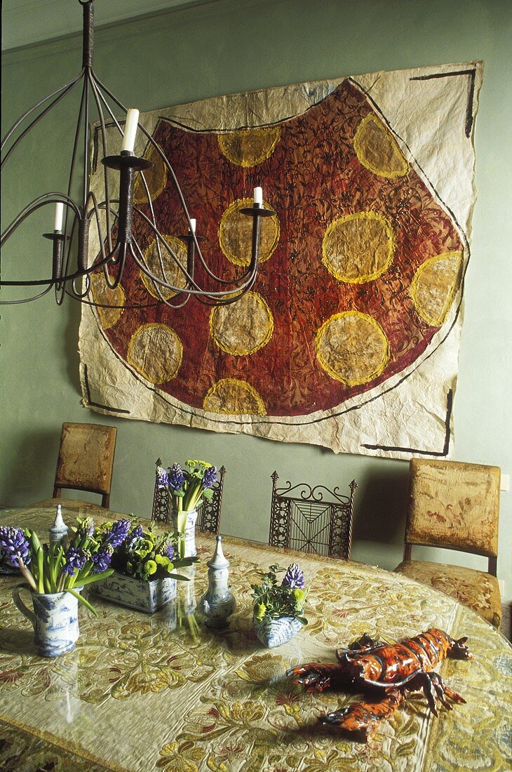 Esszimmer mit orientalischem Flair - Tisch mit Blumendeko und Bild auf grüner Wand