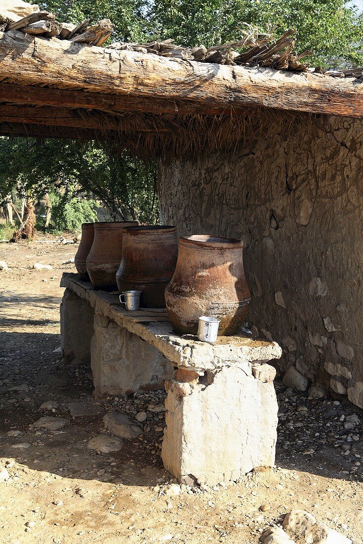 African clay planters on a stone bench under a rustic shelter, Egypt