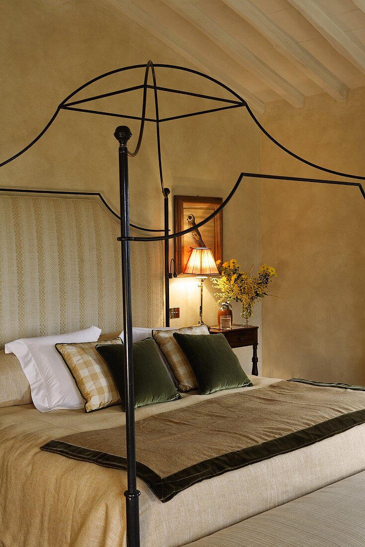 A canopy bed frame made of curved metal in a country style bedroom