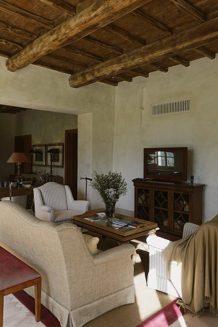 Country style living room with rustic wood beam ceiling and sofa suite