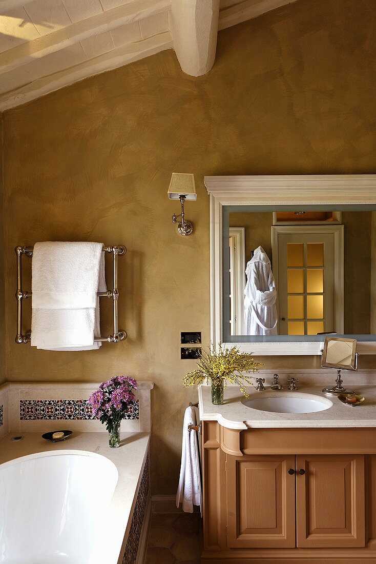 Ländliches Bad unter dem Dach mit Waschtisch und Spiegel vor gelbmarmorierter Wand