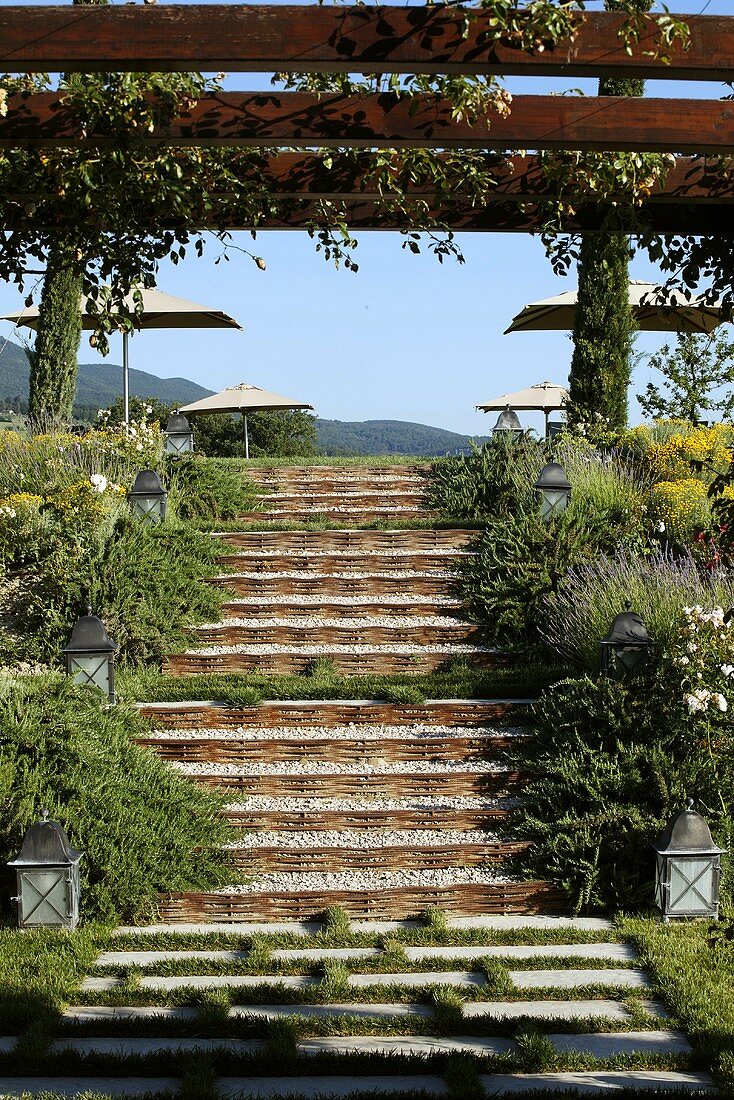 Flight of stairs and a pergola in a terrace garden with a view of a sun umbrella