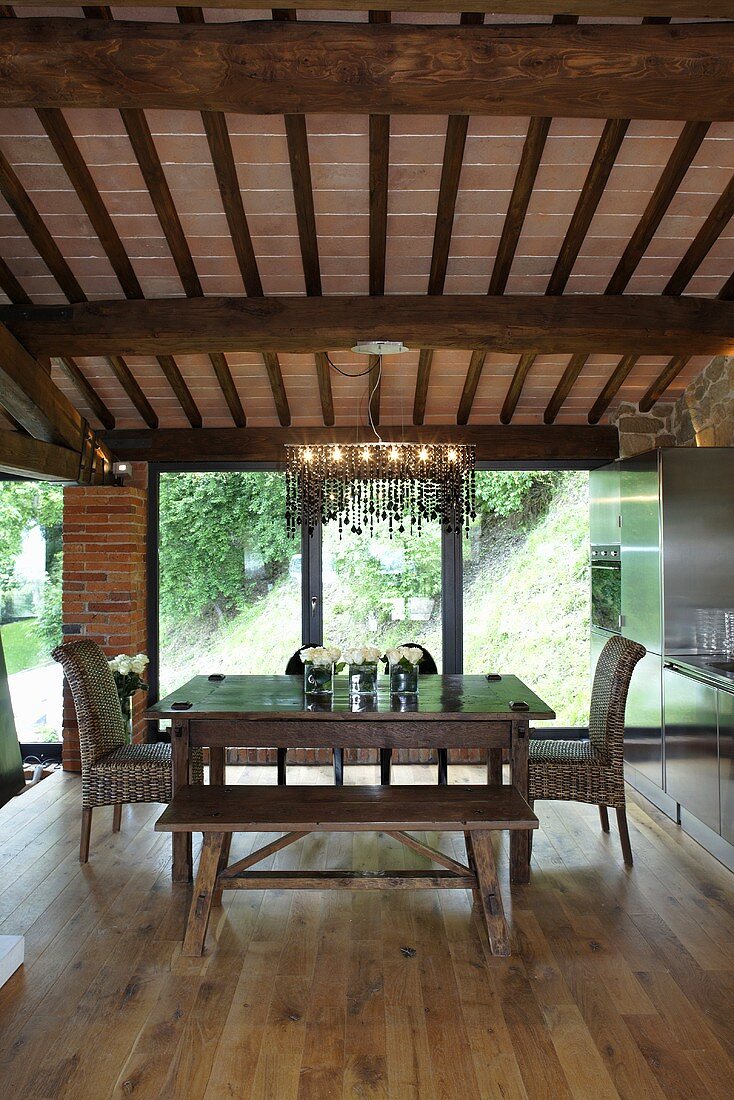 Renoviertes Landhaus - Essplatz unter Holzbalkendecke mit Designer Pendellampe vor Terrassenfenster