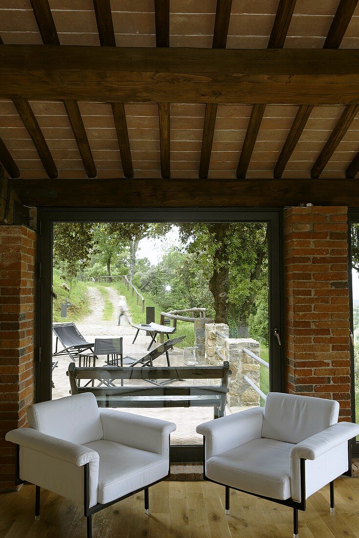 Renoviertes Landhaus - zwei weiße Sessel im Designerstil vor Terrassenfenster mit Ausblick