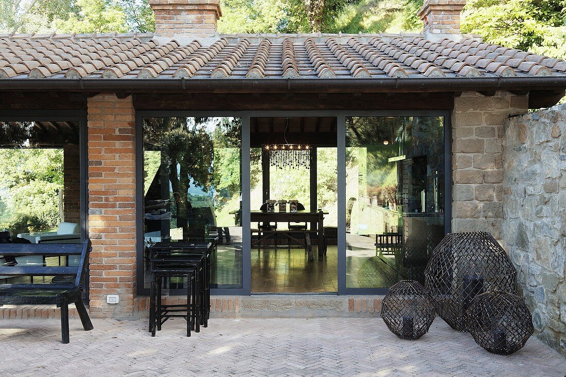Terrace with candles in large round metal grill work holders in front of a Mediterranean villa with patio doors