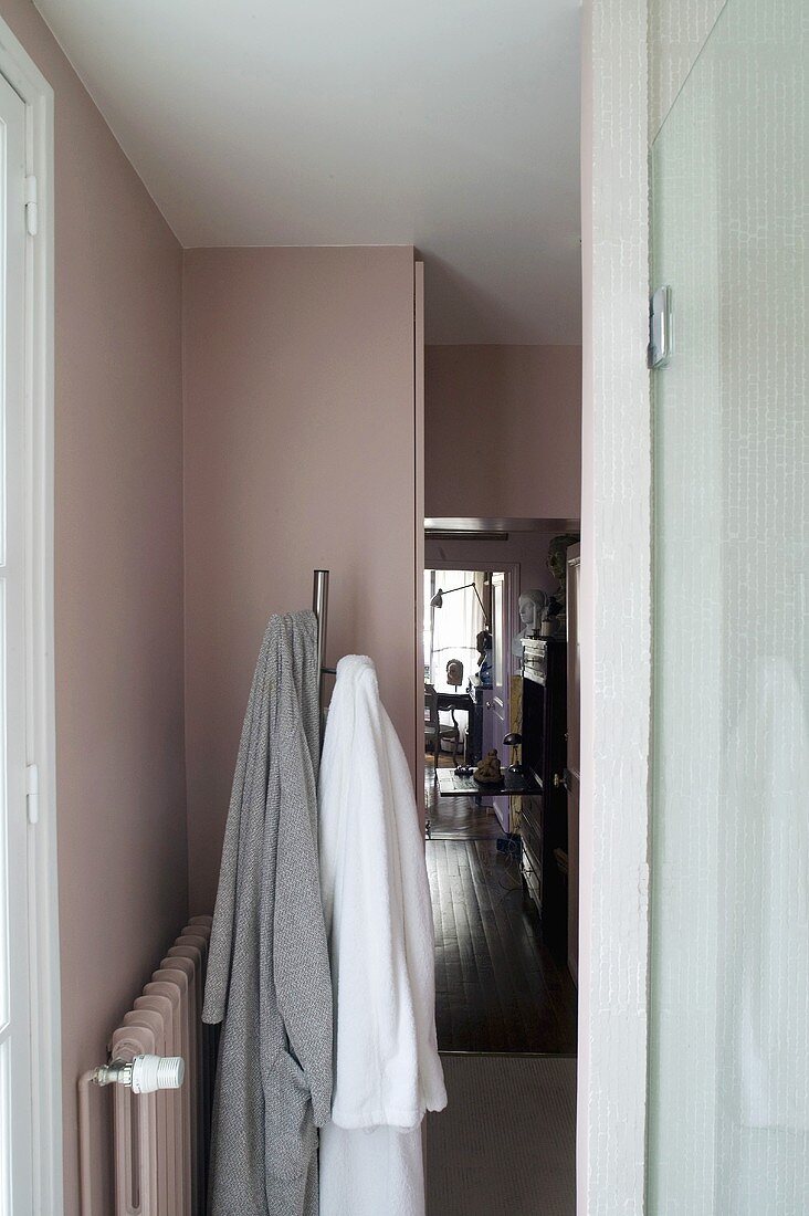 Flur - Garderobenständer mit Bademänteln vor rosafarbener Wand und Heizkörper in gleicher Farbe