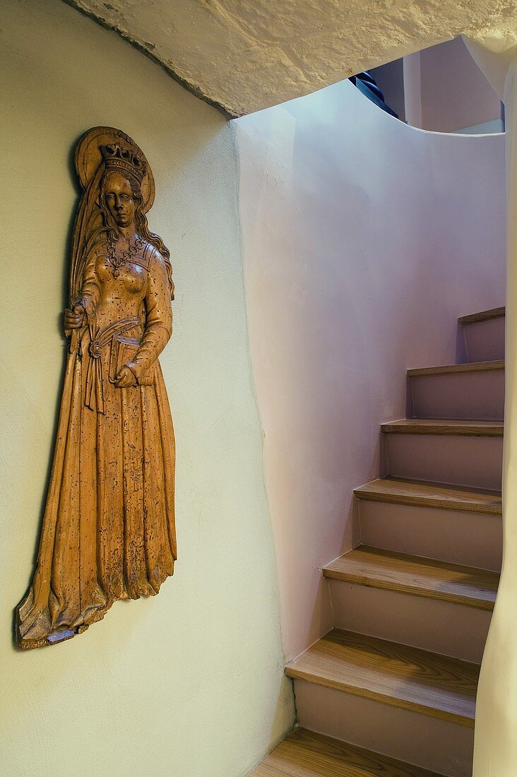 Wooden Madonna on a wall in front of a flight of stairs