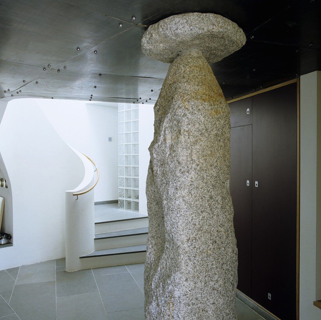 Granite sculpture in a foyer in front of a curving staircase