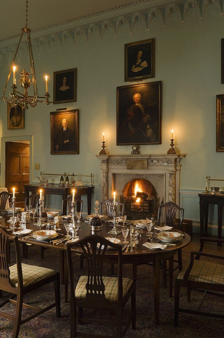 Kerzenlicht auf festlich gedecktem Tisch mit Kaminfeuer im barocken Schlosszimmer