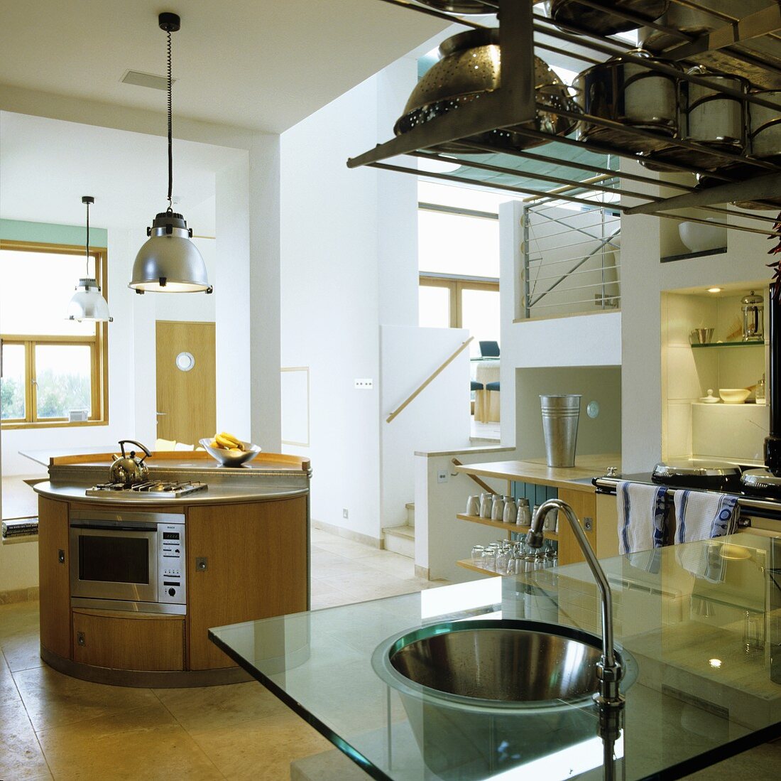 Offene Küche mit Edelstahlspüle in Glasplatte und freistehendem runden Küchenblock
