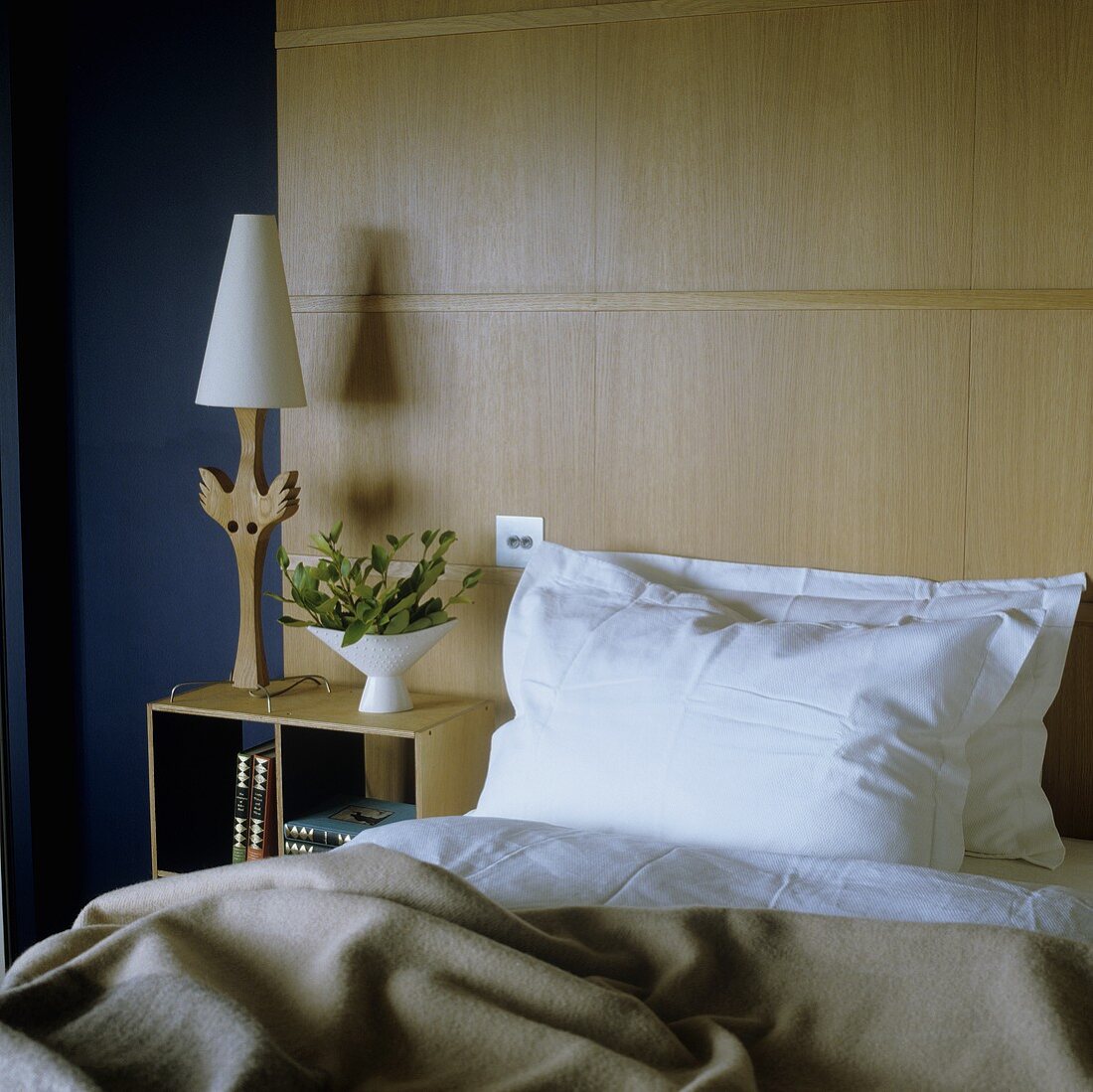 Bed in front of a wood paneled wall and night stand with table lamp