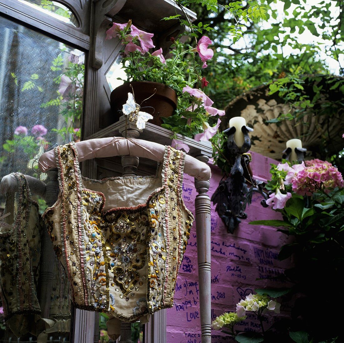 Paillette vest on a coat hanger in front of a pink wall with plant pots