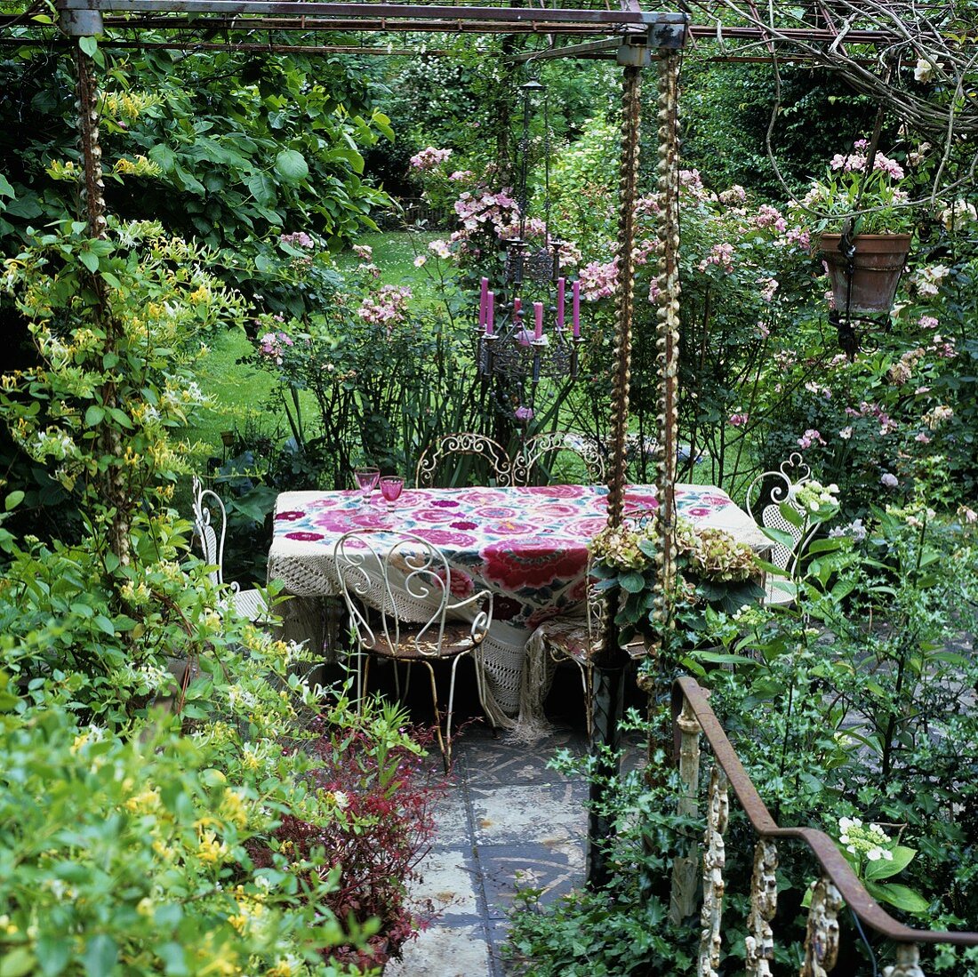 Rostige Gartenmöbel mit Blumenmuster auf Tischdecke und Kerzenleuchter