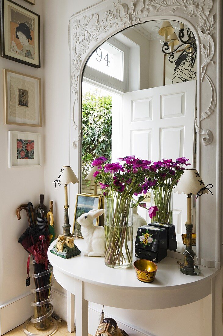Weisser Wandtisch und Blumenstrauss vor Spiegel mit geschnitztem Holzrahmen