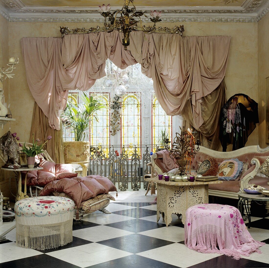 Salon im Barockschloss mit Sitzhockern und Sofa auf Schachbrettmusterboden und Fensterfront mit Vorhangschal