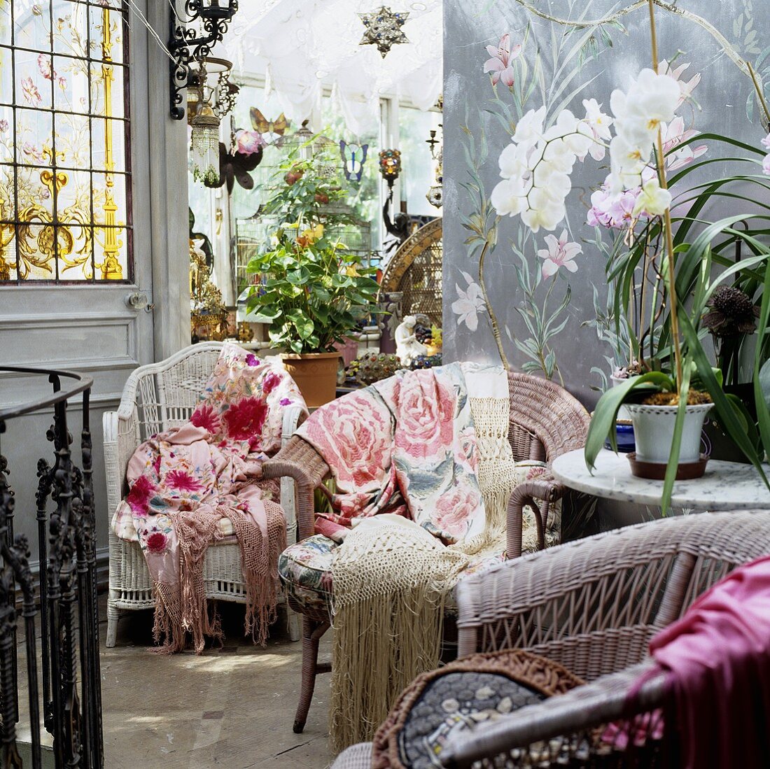 Korbstühle mit bunten Überwürfen Blumen in Töpfen im Vorraum mit Blick in Wintergarten