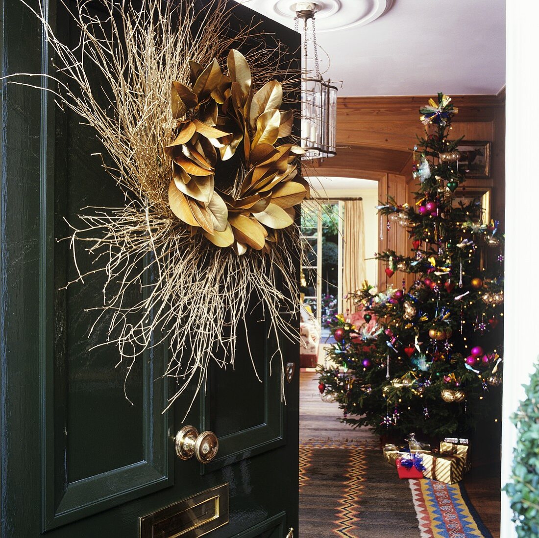 Open front door with wreath and view of a Christmas tree