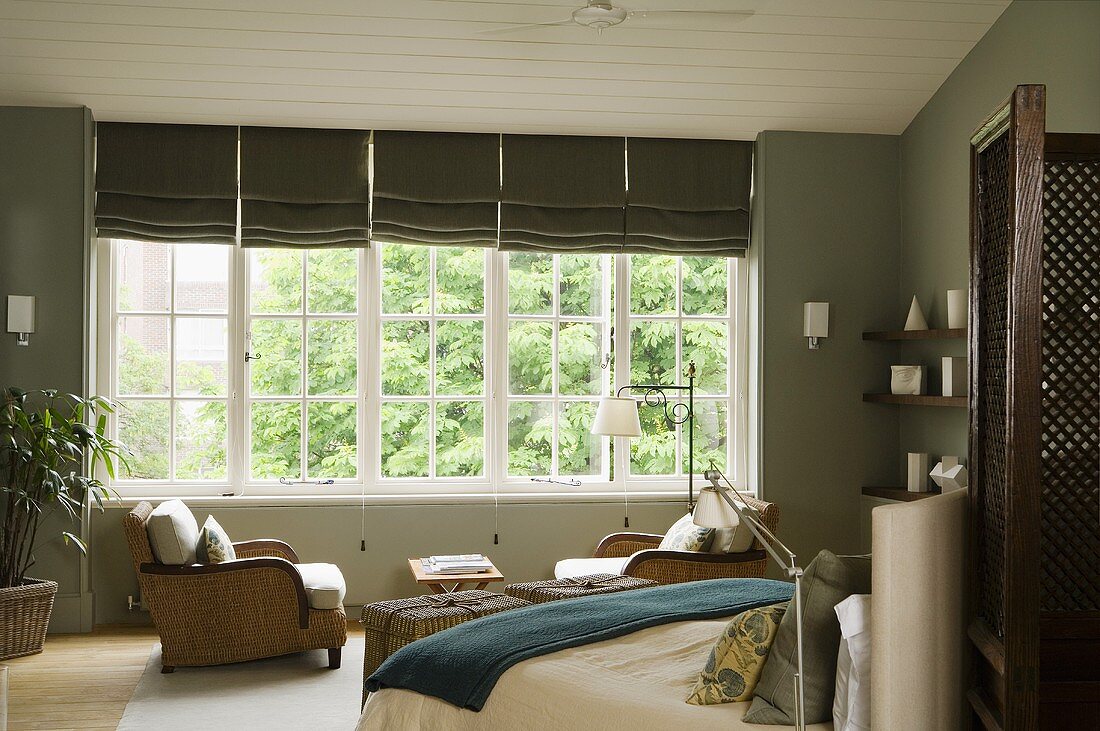 Eleganter Schlafraum mit grauen Wänden und Doppelbett vor weisser Fensterfront mit grauen Rollos