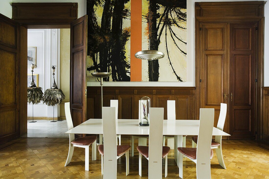 A wood panelled dining room in a villa with a white designer table and chairs