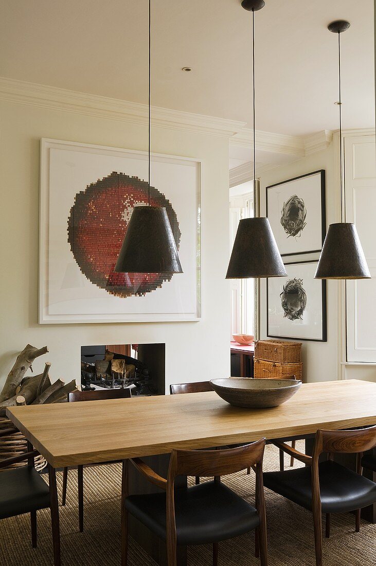 Black, retro-style metal pendant lamps above a wooden table and black upholstered wooden chairs