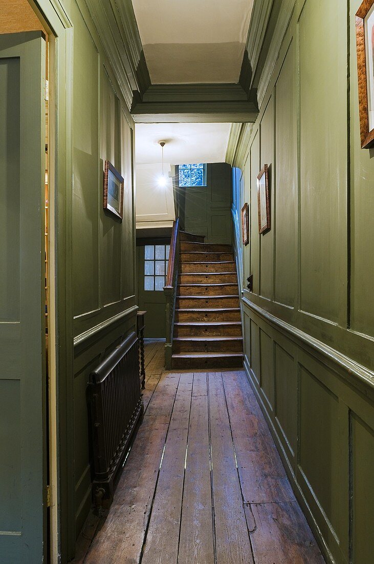 Green wood panelling in a hallway and an old wooden stairway