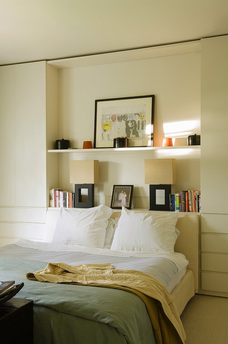 Weisses Schlafzimmer mit Doppelbett vor Regalwand in Nische