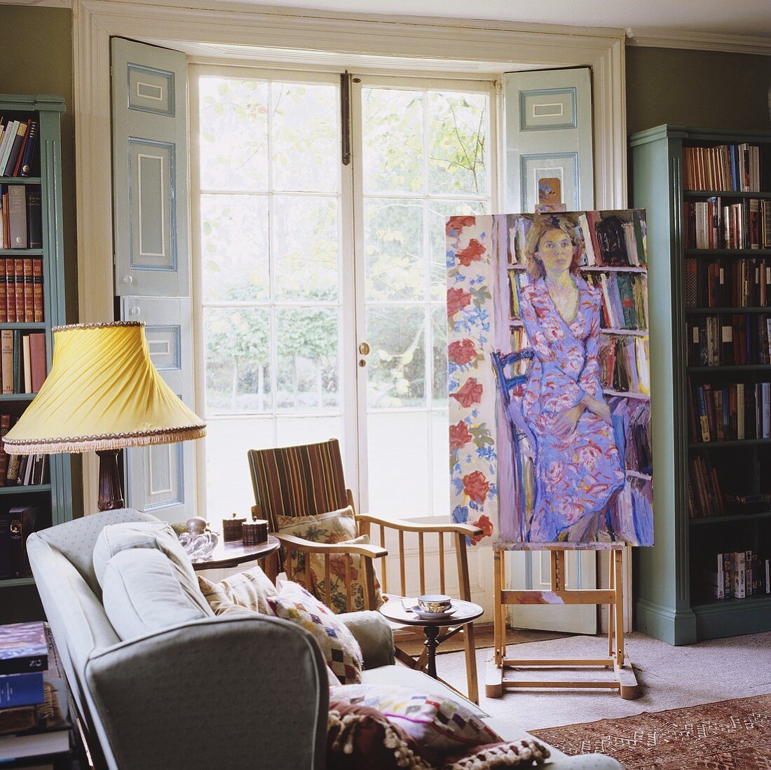 Living room in a country house with easel and picture in front of French doors with