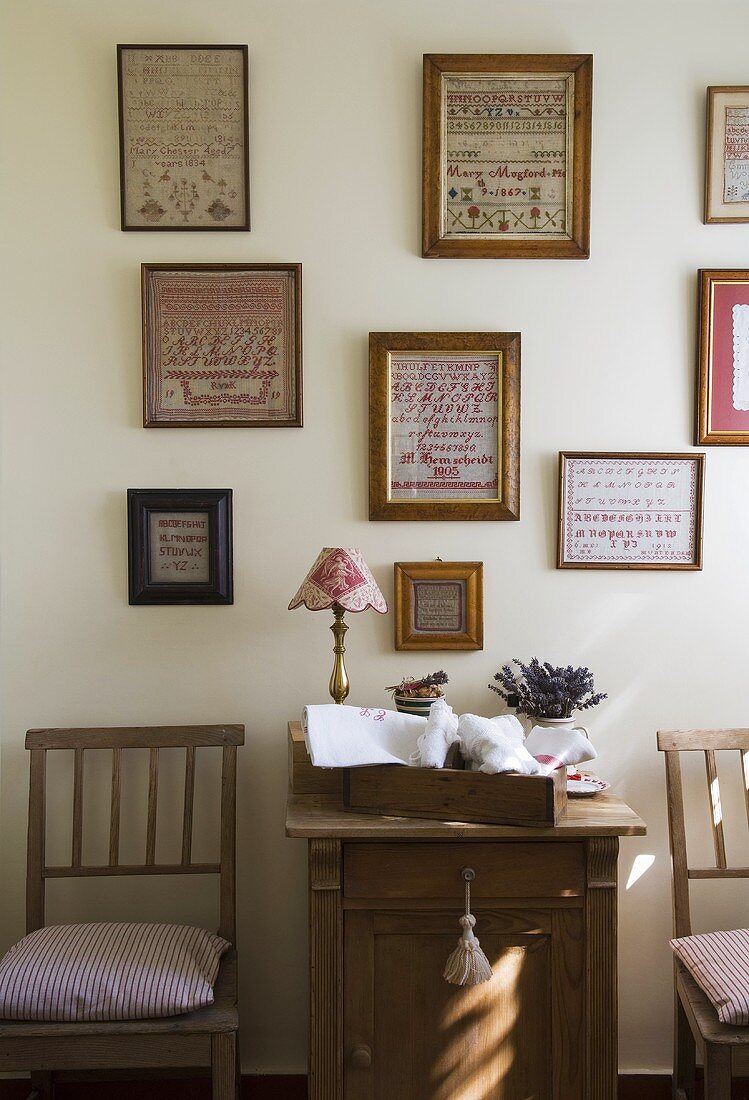 Bildersammlung an Wand über Holzschränkchen und Stuhl im Landhausstil