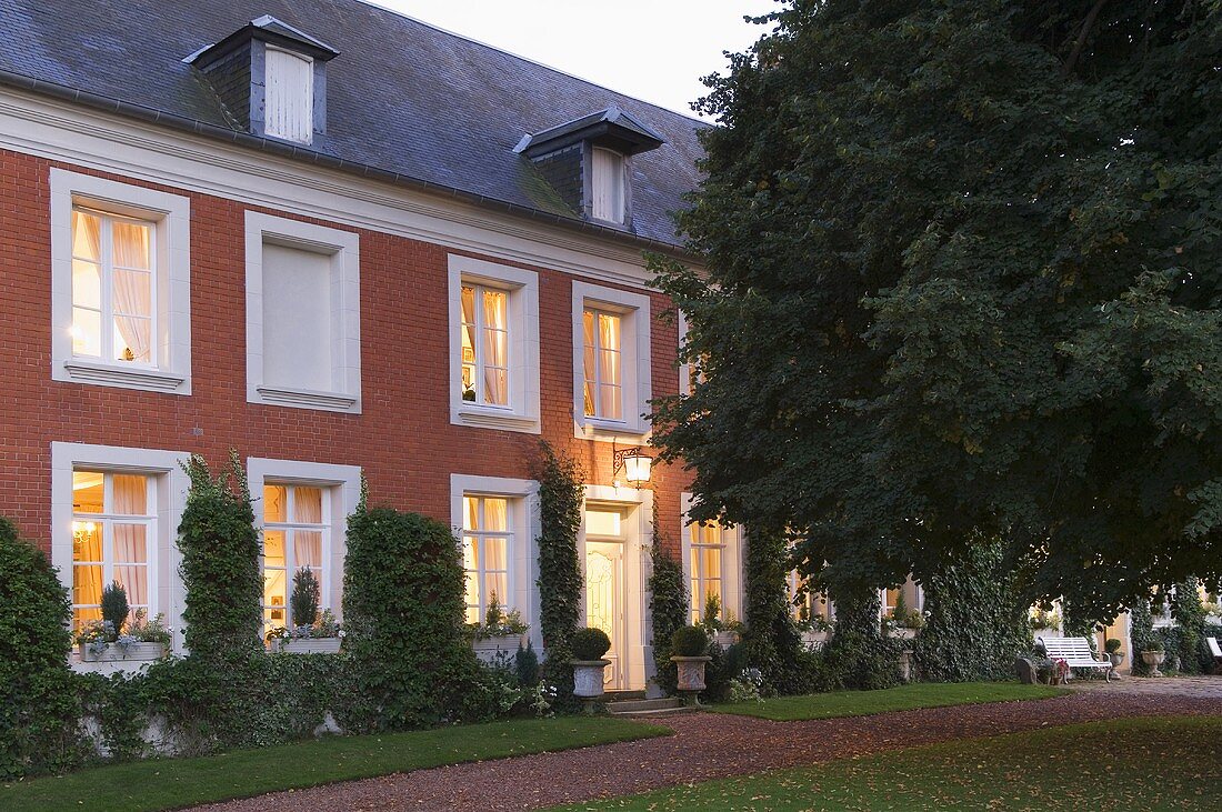 A country house with white windows and a brick facade in the evening
