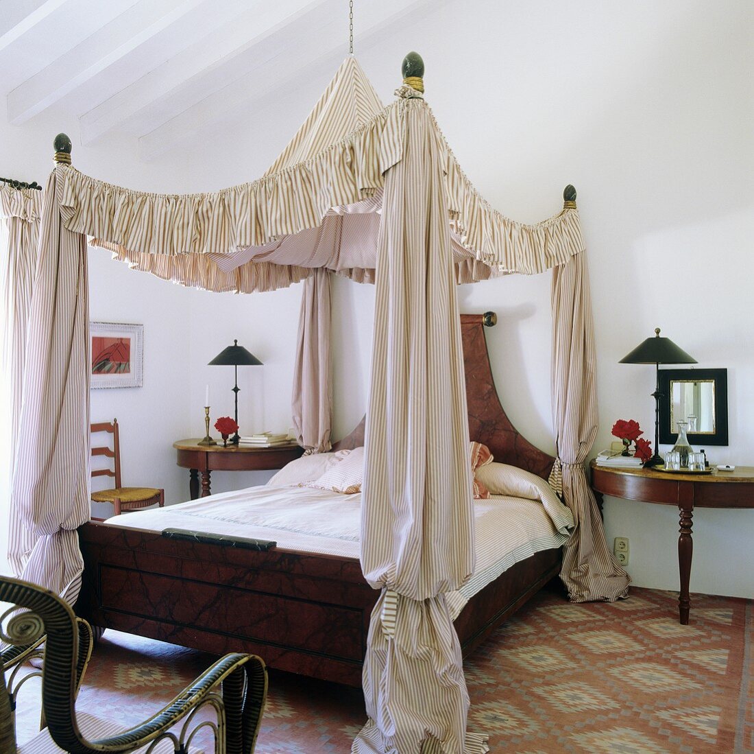 A tent-style canopy above an antique wooden bed and a bedside table on a patterned carpet