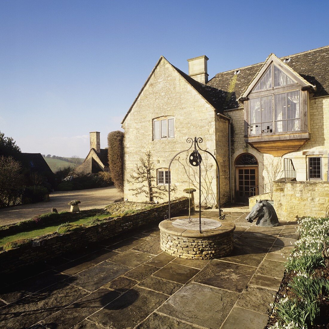 An English country house with a glazed bay window and an old decorative fountain in a courtyard