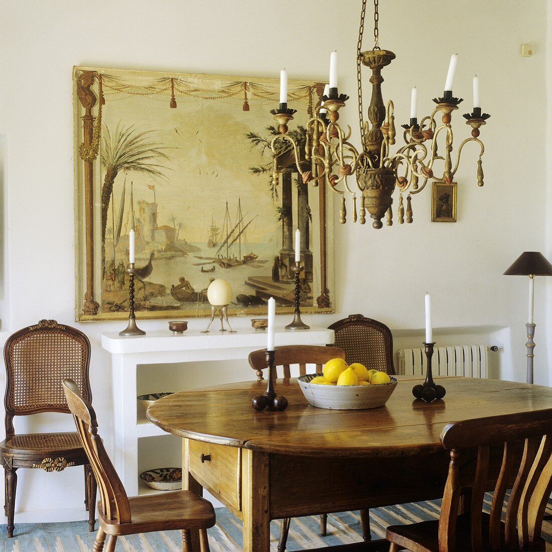 A chandelier above a fruit bowl on country house-style dining table and chairs