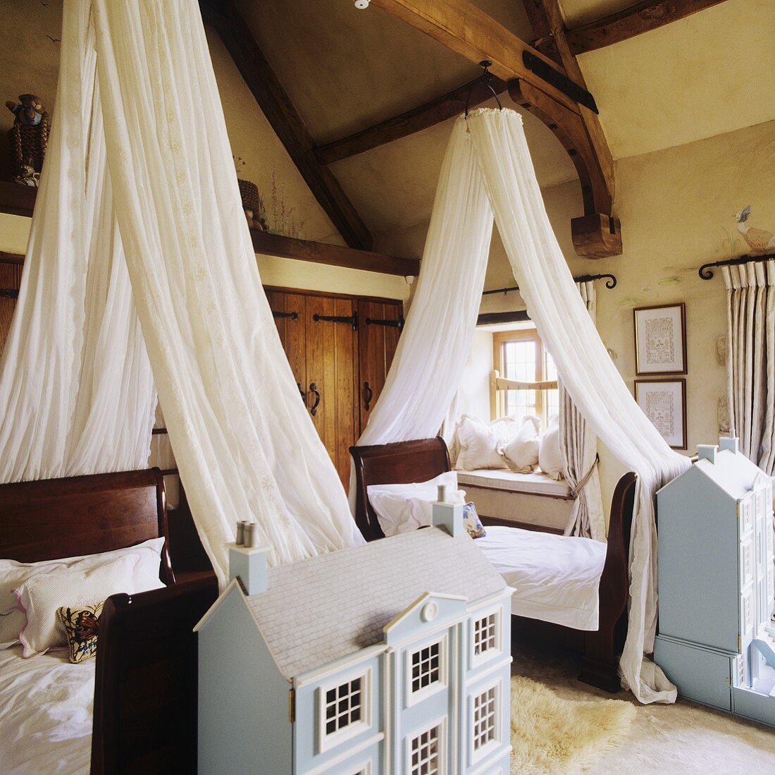 Single beds with white canopies and architectural models in a rustic bedroom