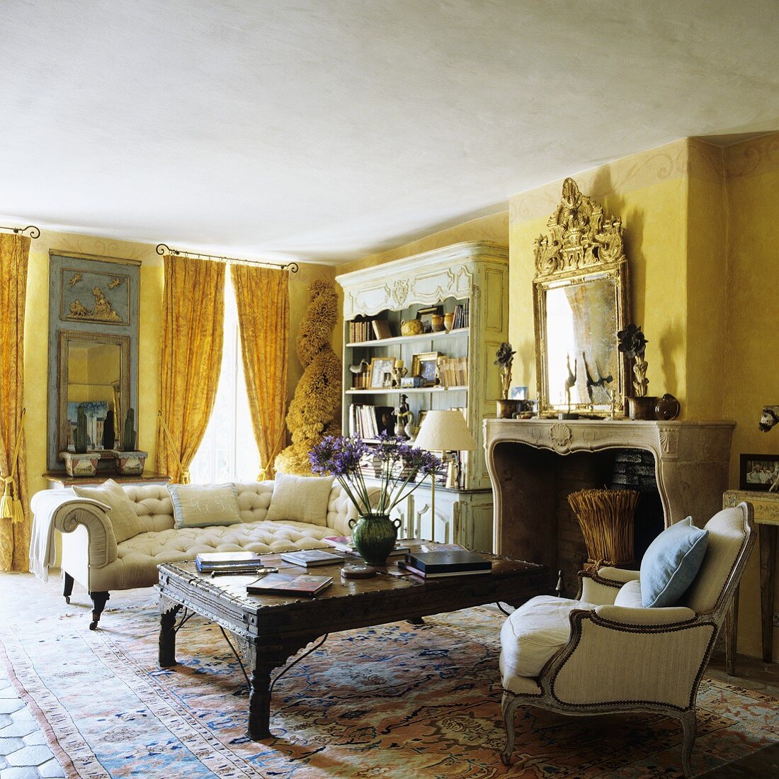 A living room with yellow walls - an antique sofa and a coffee table in front of a fireplace