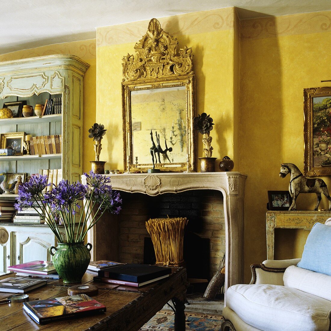 A yellow-painted living room with a fireplace and a chimney breast with a framed picture above the mantelpiece