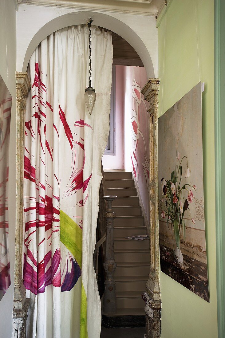 Blumenmuster auf Vorhang im Rundbogen eines Treppenhauses mit Treppenaufgang