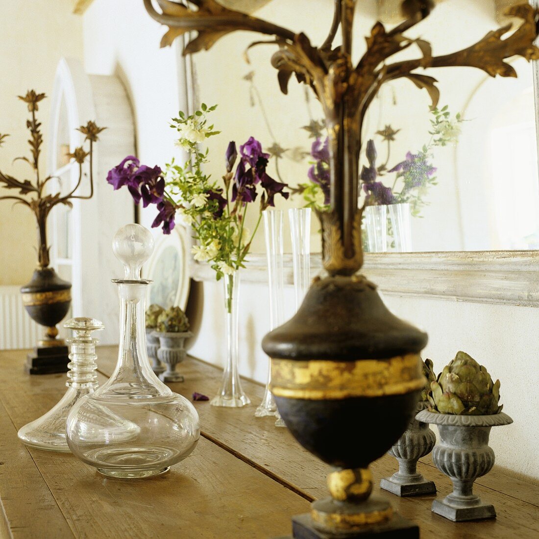 Glaskaraffe und antiker Kerzenständer auf einer Holzablage