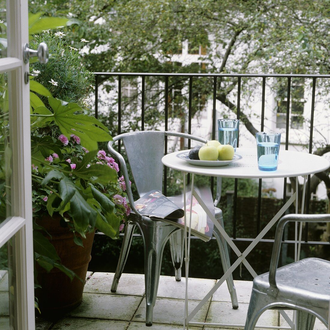 Metallstühle um Bistrotisch auf Balkon und Blick in Garten
