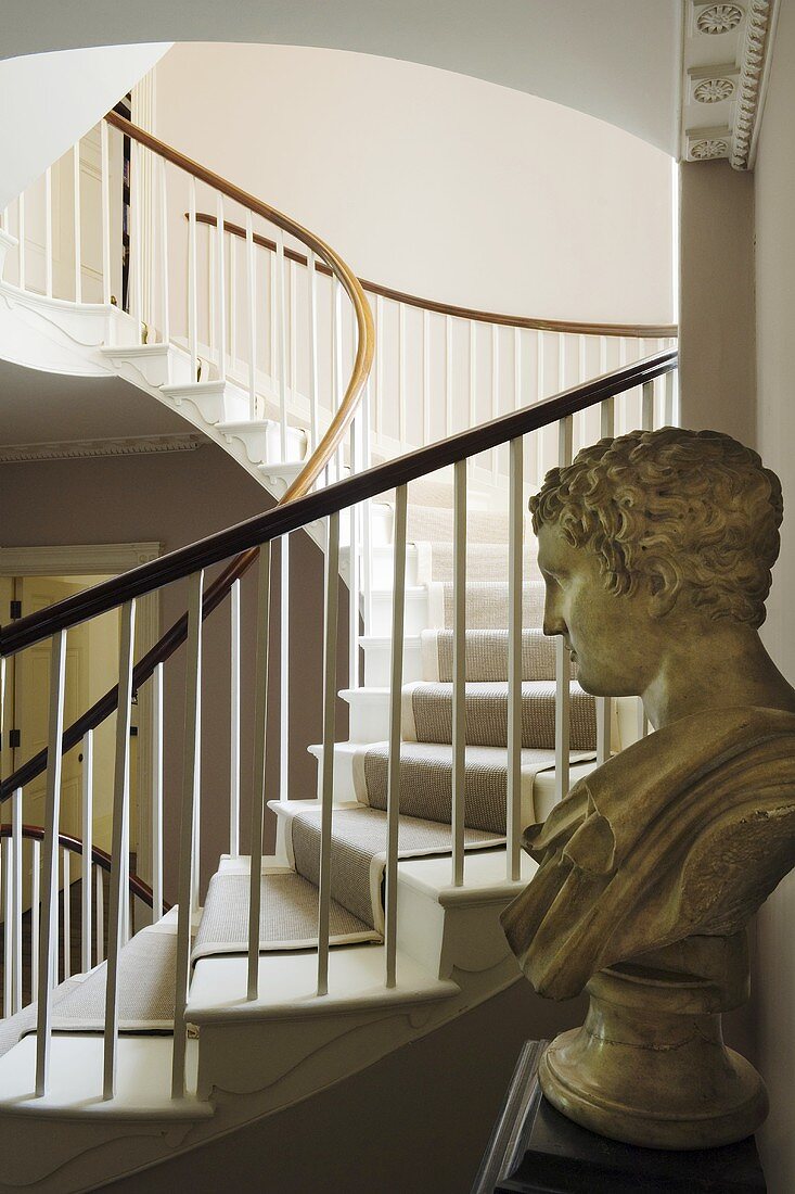 A bust and a curved stairway in the background
