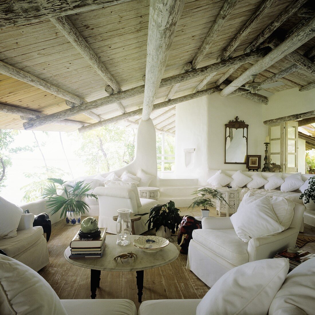 Ferienhaus in den Tropen mit rustikaler Holzdecke und offenen Ausblicken mit weisser Sofagarnitur