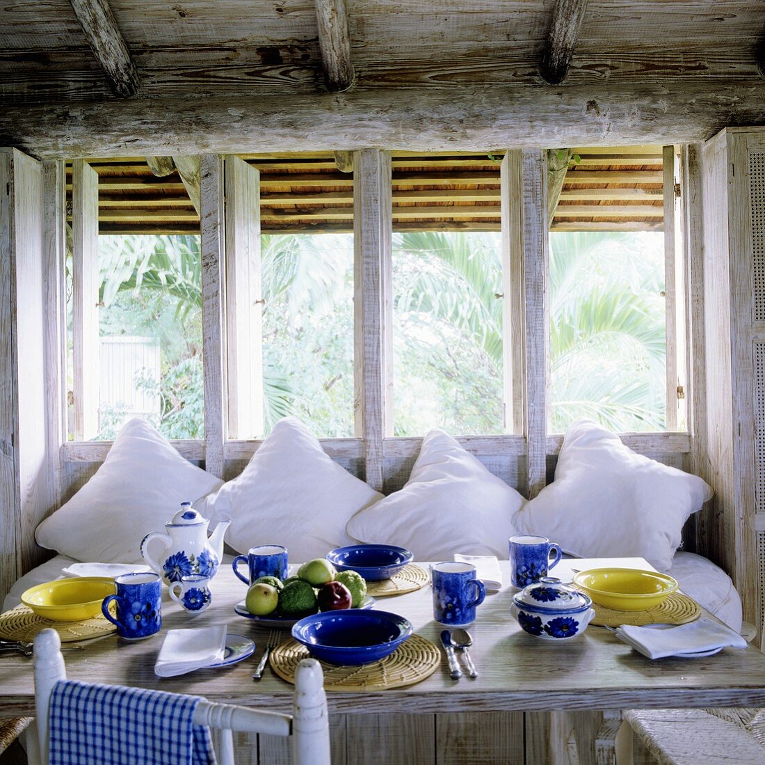 Breakfast in a rustic country house kitchen with white cushions on a comfortable bench
